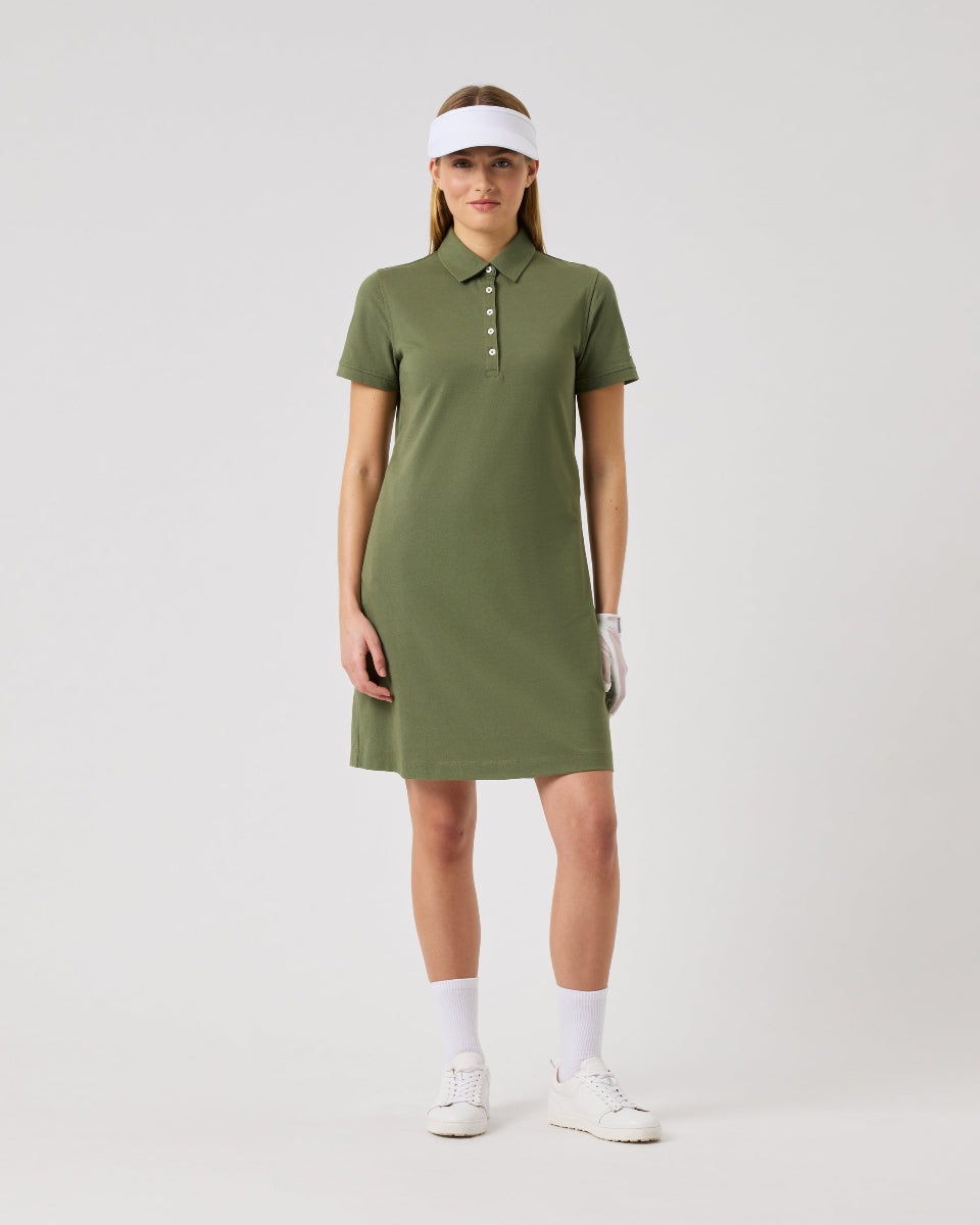 Woman wearing a green dress and white visor on a light gray background