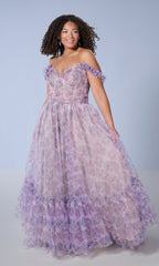 A woman wearing the Tiffany 16162 long plus-size prom dress, an off-the-shoulder, lavender floral print gown with a corset bodice, stands against a light blue background.