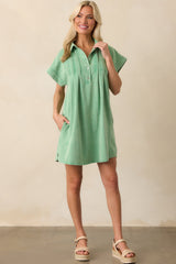 Mini dress in light green, featuring a collared neckline, short sleeves, and functional pockets, designed with pin tuck detailing along the front for a structured look.