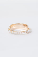 A gold ring with a flat wide backing and a single row of pave white diamonds around the front half of the band, displayed against a white background.