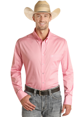 A man stands smiling with one hand in his pocket against a white background, wearing a Rock & Roll Denim Regular Fit Pink Long Sleeve Button Shirt, blue jeans, a black belt, and a straw cowboy hat.