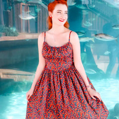 Woman in a floral dress standing by a pool with fish