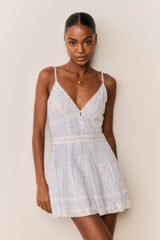 Woman wearing a light blue lace dress against a plain background