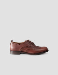 A single brown leather brogue with heel pull detail and contrast leather lining. Side angle flat lay view.