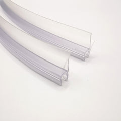 Nahaufnahme Ablaufprofil-Set der Marke HÜPPE bestehend zwei gebogenen, transparenten, schmalen, länglichen, U-förmigen Kunststoffprofil, mit einem überlappenden Ablaufschutz an der Profilunterseite, vor weißem Hintergrund.
