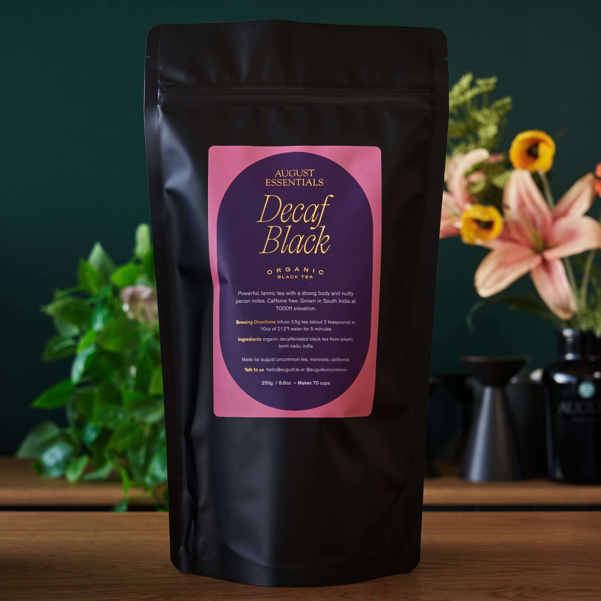 August Essentials Decaf Black Black Tea in a 70 cup bag, shown in packaging with tea leaves visible.