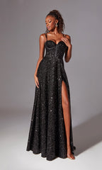 A woman poses against a plain gray background wearing the Aerie Couture 273, a long black glitter prom dress with a corset-style bodice and thigh-high slit.