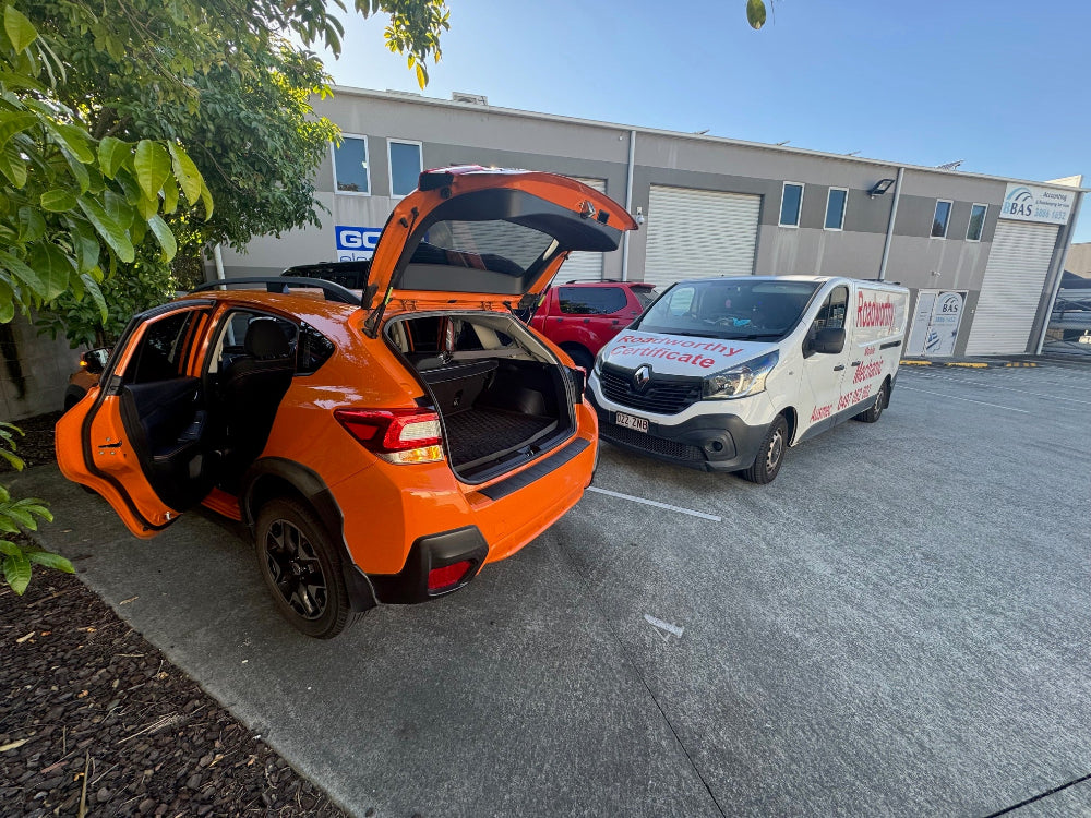 Our team meticulously inspecting a car with the bonnet and doors open, as part of a detailed pre purchase car inspection near Clontarf. Orange SUV with open trunk in a parking lot with a white van in the background.
