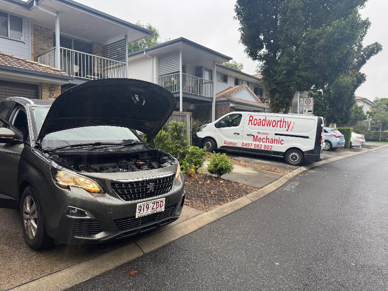 Car with open hood on a residential street, Roadworthy van parked nearby. Performing a professional pre purchase car inspection on a car at a seller's house for your peace of mind.