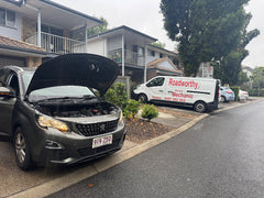 Car with open hood on a residential street, Roadworthy van parked nearby. Performing a professional pre purchase car inspection on a car at a seller's house for your peace of mind.