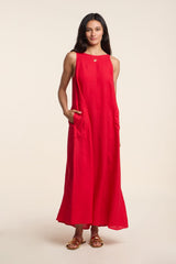 A woman poses against a plain light background in the RETA LINEN DRESS by Velvet by Graham & Spencer—a sleeveless, ankle-length maxi with side pockets, styled with flat sandals and a necklace for effortless warm-weather dressing.