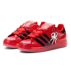 SP5DER x ADIDAS SUPERSTAR in glossy red patent leather with black stripes and a silver spider charm.