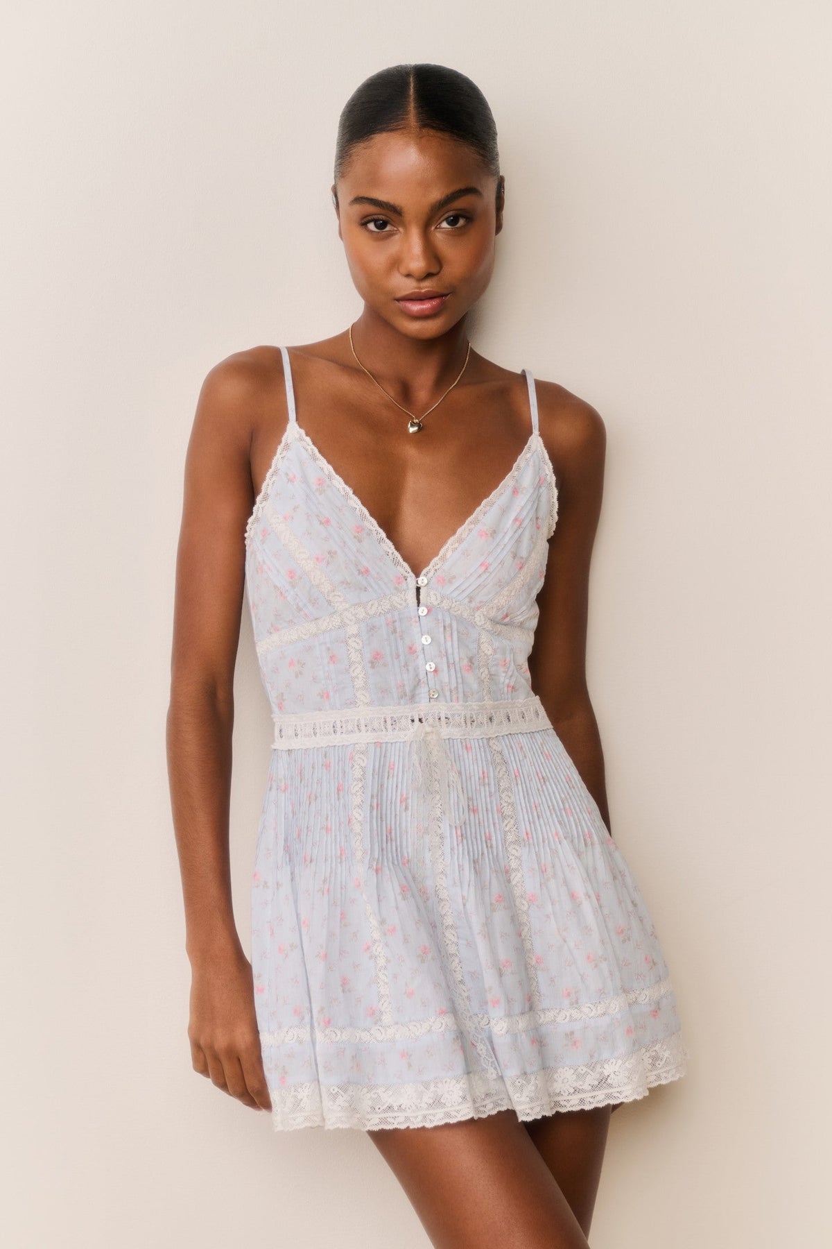 Woman wearing a light blue lace dress against a plain background