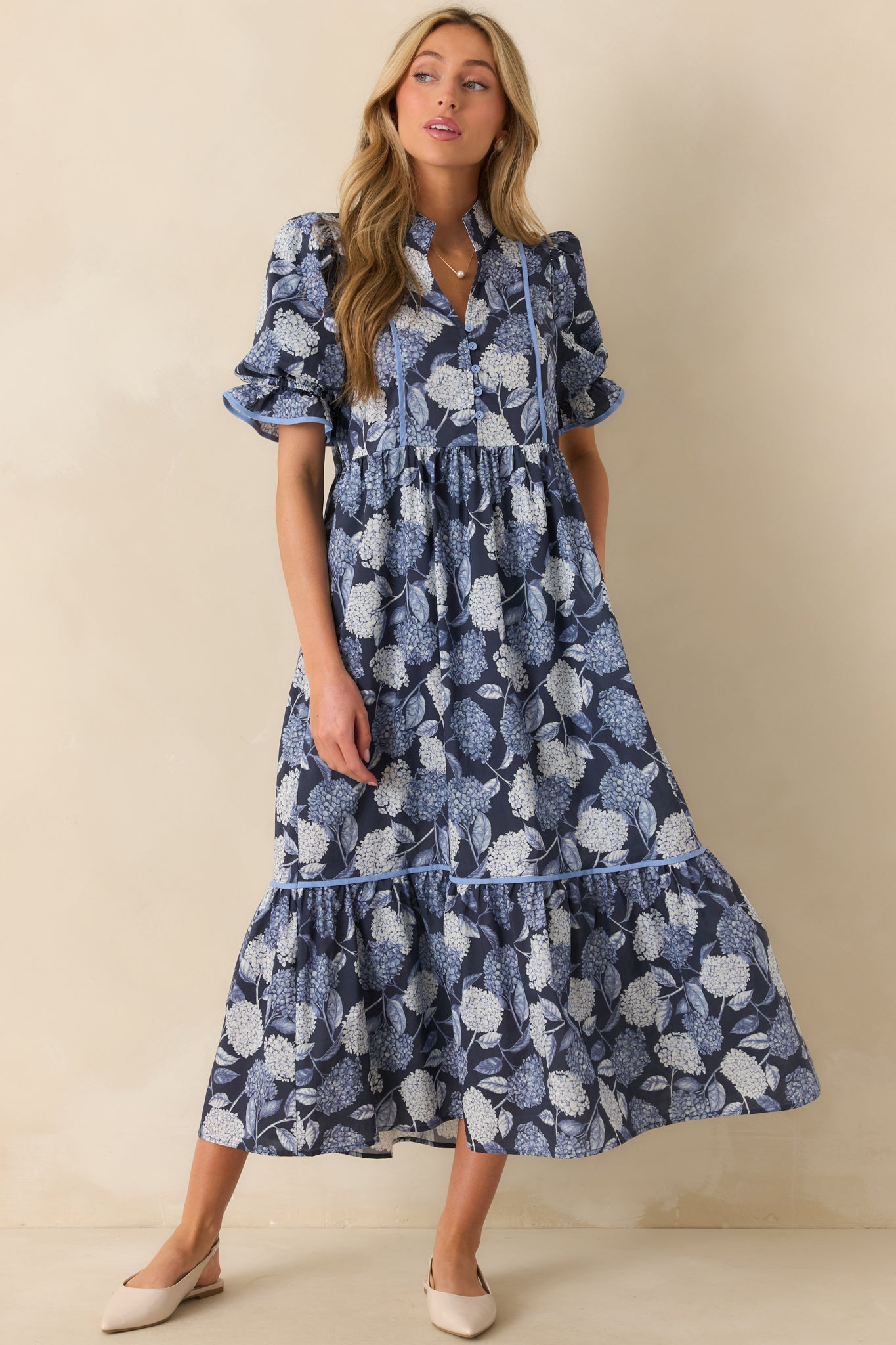 A full view of the blue hydrangea print maxi dress with a notch v-neckline and button front bust.
