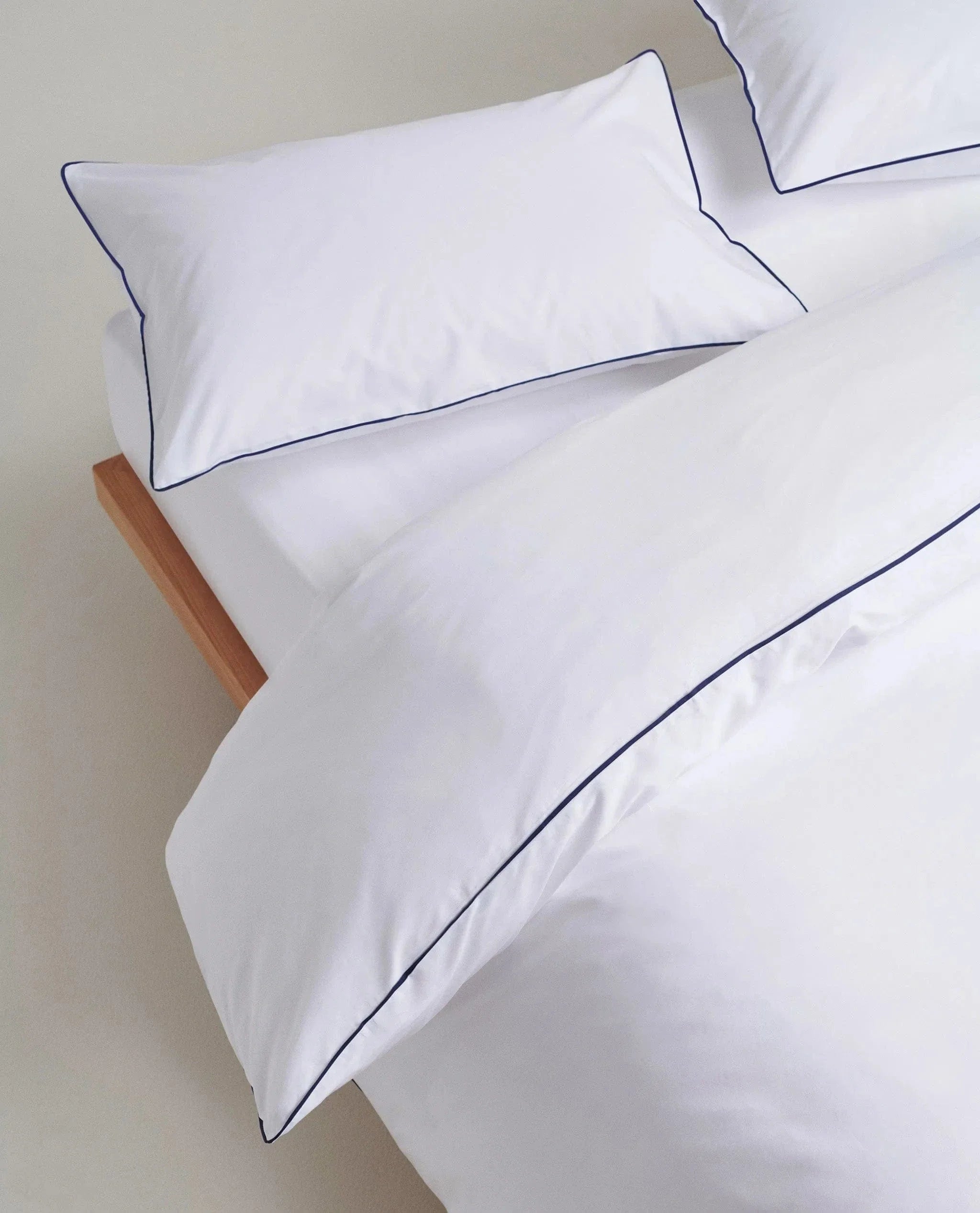 image 3 of 5 showing close up of Rise & Fall's Soft & Smooth duvet set, colour: white with navy piping, fabric: sateen cotton