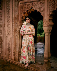 A floral jaal print kaftan set in Paulmi and Harsh signature ivory chintz floral print, featuring a pair of birds in their enchanting habitat. It has a V neck, hand-embroidered patch border, drop sleeves, front slit and elastic gathers to accentuate the waist. The border is hand-embroidered in zardozi. It is paired with straight cut printed pencil pants.